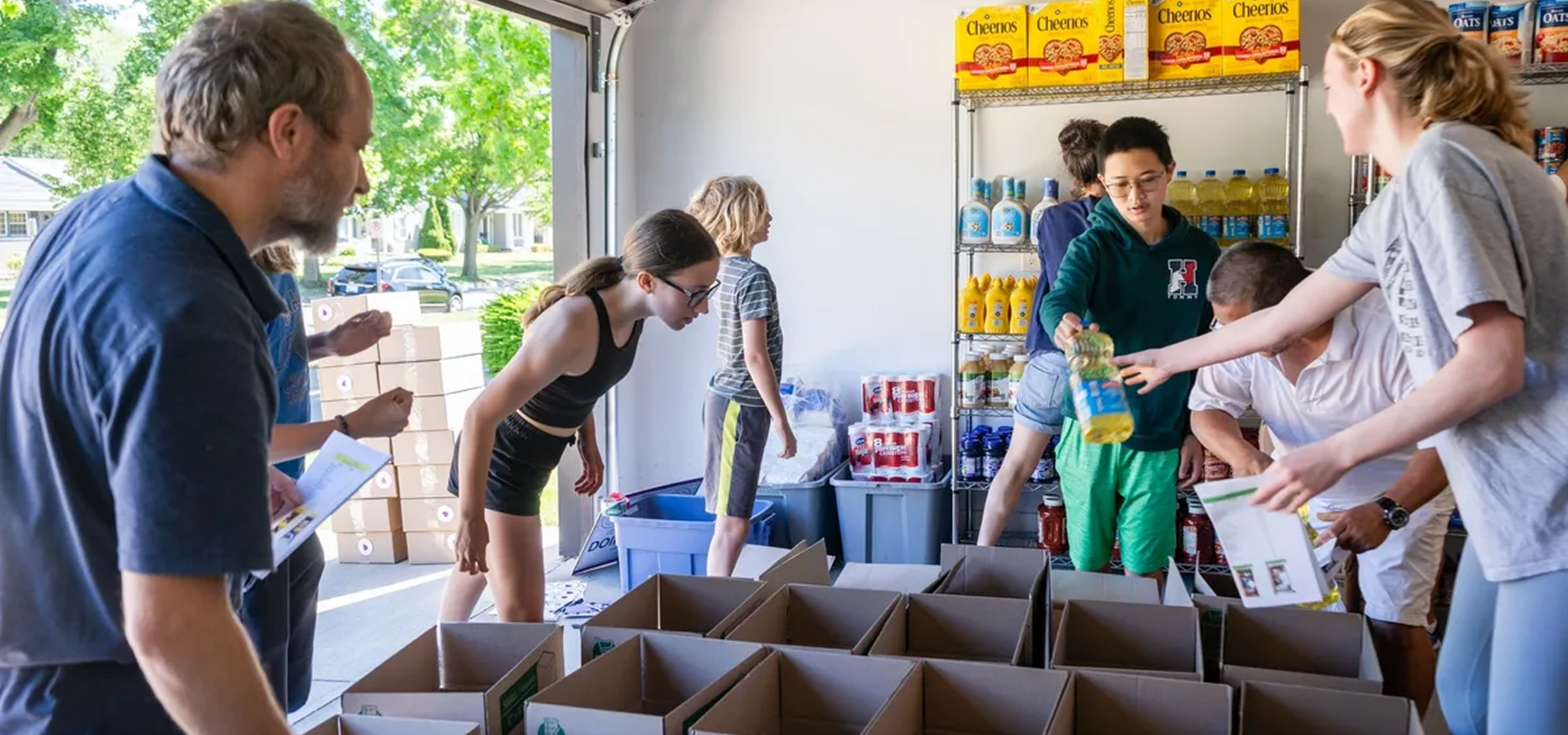 People packing food boxes in a garage.